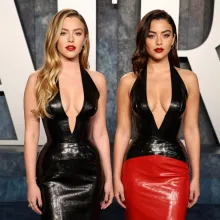 The image is a split-style photograph featuring two women standing next to each other against a background that appears to be a red and gray patterned wall. On the left side of the image, one woman is wearing a black strapless dress with a high neckline a