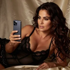 Sultry boudoir photography Salma Hayek looking at iPhone.. Silks, elegant lingerie, seductive
