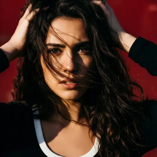 A dramatic close-up portrait of a young woman with dark wavy hair