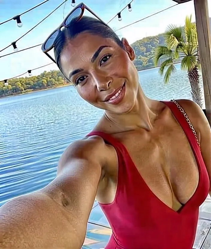A woman takes a selfie outdoors near a calm body of water